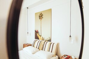 A bedroom with a bed, a nightstand, a lamp, and a painting on the wall. - we saw athens from 4b (Athina)