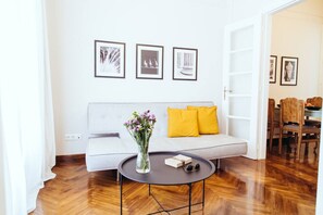 A living room with a sofa, a coffee table, and framed pictures on the wall. - we saw athens from 4b (Athina)