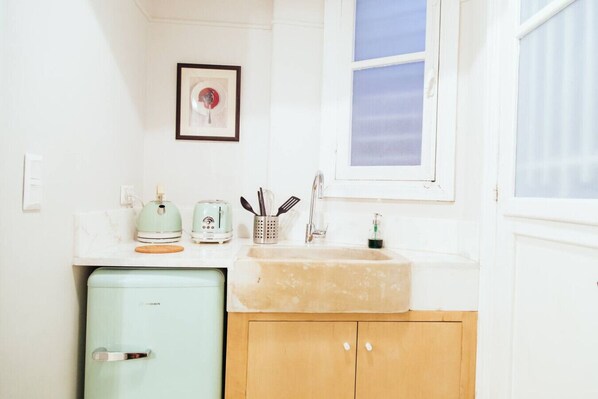 A compact kitchen with a vintage toaster, a sink, and a small refrigerator. - we saw athens from 4b (Athina)