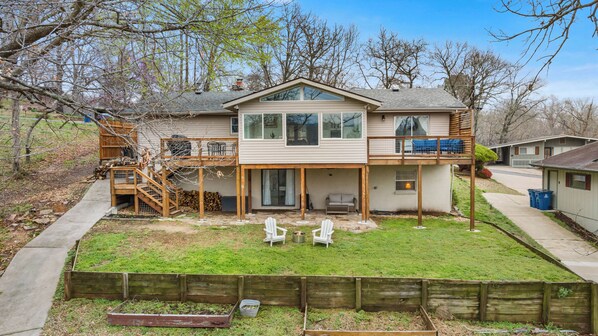 A two-story house with a covered patio, a wooden deck, and a fenced backyard.