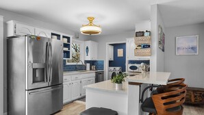 A modern kitchen with a stainless steel refrigerator, white cabinetry, a granite countertop, and a wooden chair. - Lakeside Pines: Waterfront > Bike in/out > Game Room > Fitness Room (Bella Vista)