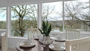 A dining table with white chairs, a potted plant, and white dinnerware set. - Lakeside Pines: Waterfront > Bike in/out > Game Room > Fitness Room (Bella Vista)