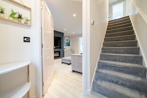A staircase leading to a living area with a fireplace, a sofa, and a coffee table. - Lytham St Annes FY8 | 3BR Home | Near Blackpool (Lancashire)