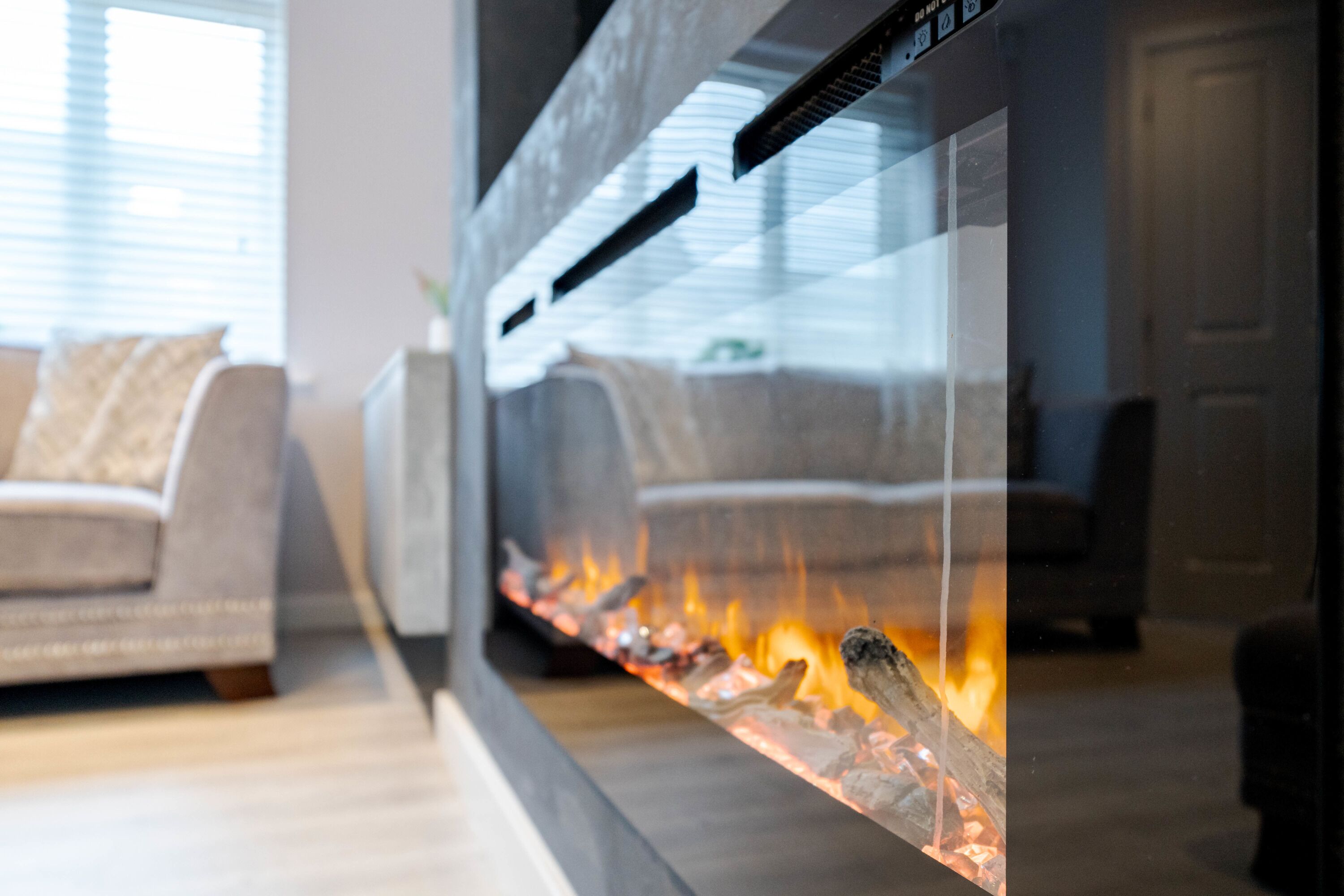 A modern living room with a glass fireplace, a sofa, and a coffee table.