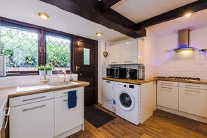 Une cuisine compacte équipée d’un lave-linge, d’un four à micro-ondes et d’une cuisinière à gaz.