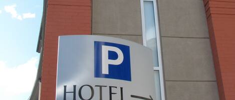 A hotel sign with a parking symbol and an arrow indicating direction.