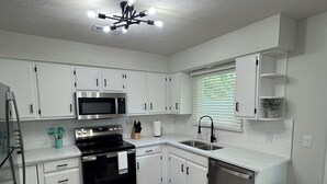 Una cocina moderna con armarios blancos, electrodomésticos de acero inoxidable, una estufa negra y un lavavajillas.