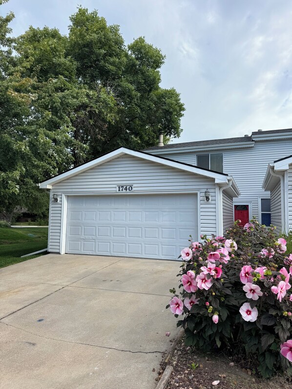 A residential garage with a number '1740' on the door, a red door, and a driveway leading to the garage.