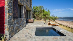 A stone building with a pool, outdoor seating, and a view of the beach and ocean. - Direct Beach Access!! - Casa On The Rocks Uruguay (Estación Las Flores)