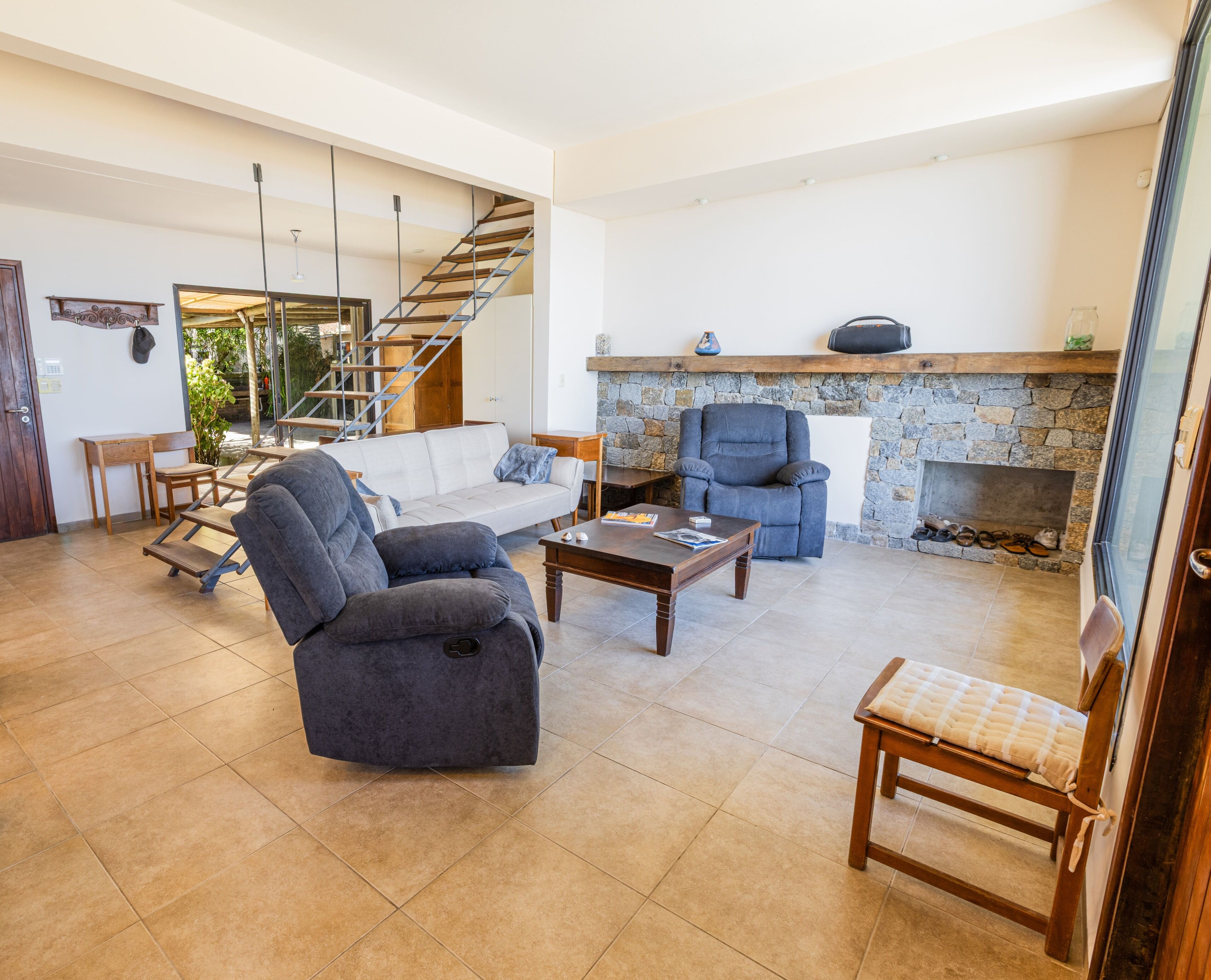 A spacious living area with a sofa, armchair, coffee table, fireplace, and a staircase.