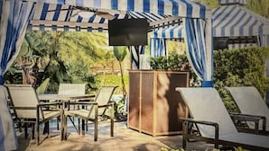 Un espacio de estar al aire libre cubierto con toldos a rayas, una mesa de madera y sillas.
