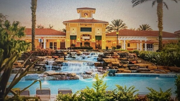 Un hotel con piscina, cascada y palmeras.