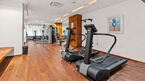 Ein Fitnessraum mit Laufbändern, Crosstrainern und Gewichtsgeräten.
