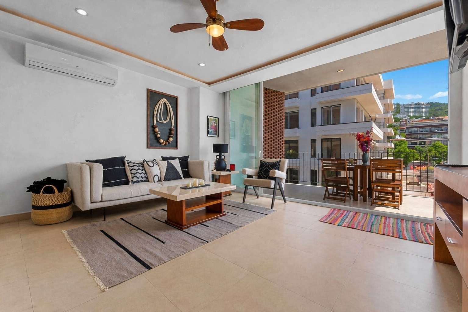 A modern living room with a sofa, coffee table, and a dining area with chairs and a table.