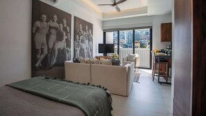 Ein modernes Hotelzimmer mit einem großen Bett, einer Sitzecke, einem Fernseher und einem Balkon mit Blick auf die Stadt.