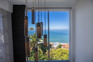 A room with a large window overlooking the sea, a black textured wall, and hanging decorative lanterns. - Spectacular Casa de dos Davids (Puerto Vallarta)