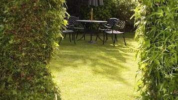 A garden with a table and chairs, surrounded by greenery.
