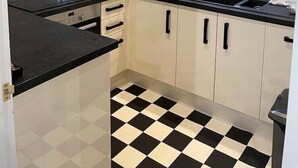 Una cucina compatta con pavimento a scacchi bianco e nero, una finestra vista e una cappa aspirante in acciaio inossidabile.