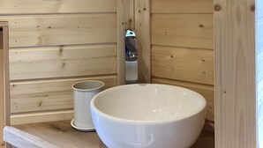 Un intérieur en bois avec un grand récipient blanc et un petit contenant blanc, probablement un porte-savon, posés sur une étagère en bois.