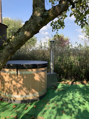 Ein Whirlpool mit Holzverkleidung, einem Metallschornstein und einem Grünstreifen.