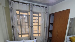 Een slaapkamer met een bed, gordijnen, een kledingkast en een spiegel.