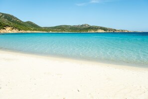 A beach with clear turquoise water, white sand, and green hills in the background. - Brabara Vacation Home - Wellore - Historic House in the Center of Teulada (Teulada)