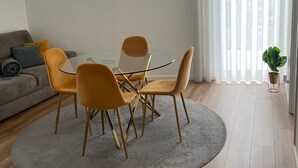Una sala de estar moderna con comedor, un sofá y un ventanal con cortinas.