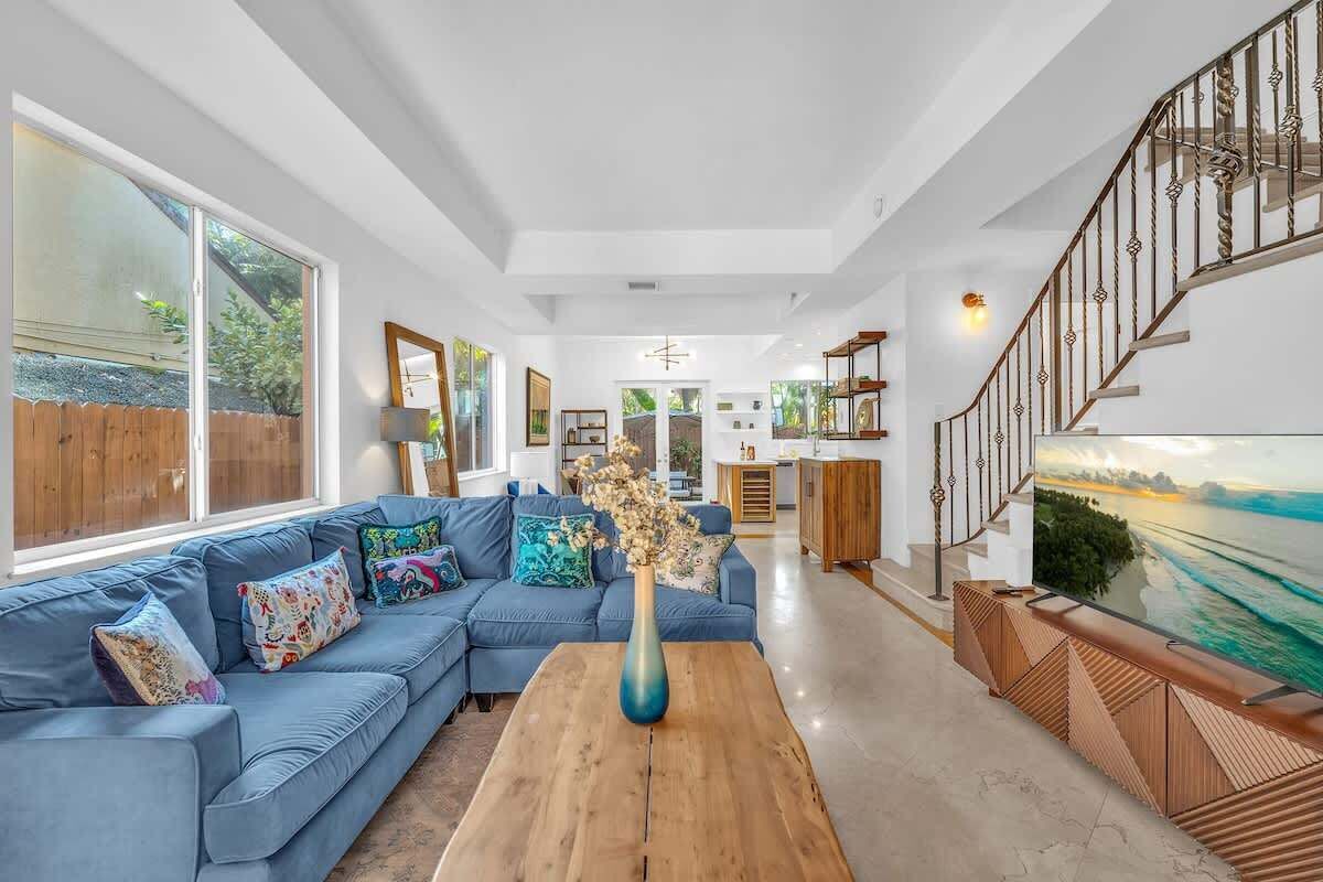 A spacious living room with a blue sofa, a wooden coffee table, and a large window.