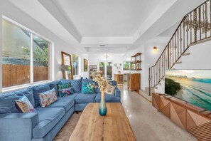 Ein geräumiges Wohnzimmer mit einem blauen Sofa, einem Holztisch und einem großen Fenster.
