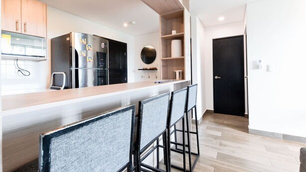 Une cuisine moderne avec un coin bar, des meubles en bois et une porte noire.