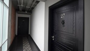 Un couloir avec un sol à motifs, une porte noire portant le numéro 27 et une autre porte portant le numéro 28.