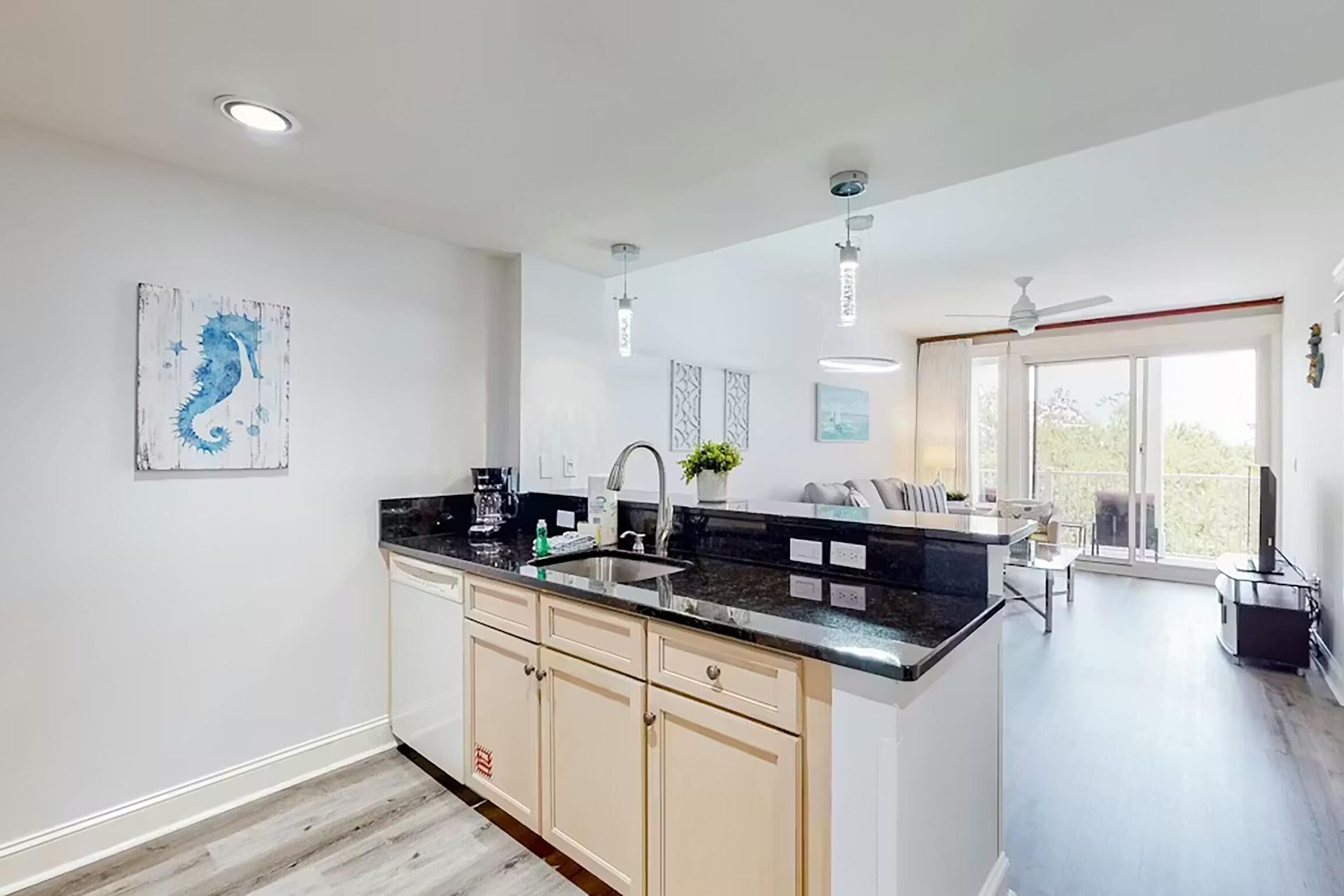 A modern kitchen with a central island, a sink, and a dining area with a view.