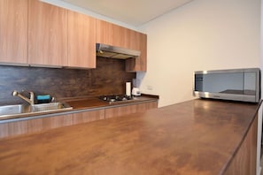 Una cucina moderna con mobili in legno, lavello in acciaio inossidabile, piano cottura integrato e forno a microonde.