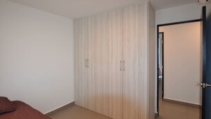 Une chambre à coucher avec une armoire, un lit et une porte donnant sur une autre pièce.