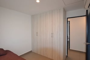 Quarto com guarda-roupa, cama e porta que dá para outro cômodo.