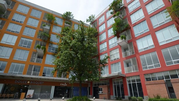 Un bâtiment moderne doté d’une cour intérieure, où l’on trouve un arbre et une enseigne indiquant « Dolce Bisquet ».