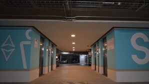 Un couloir aux murs de couleur turquoise, avec de grandes lettres « S » et une voiture garée au fond.