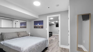 A modern bedroom with a large bed, a mirror, and two cityscape pictures on the wall.