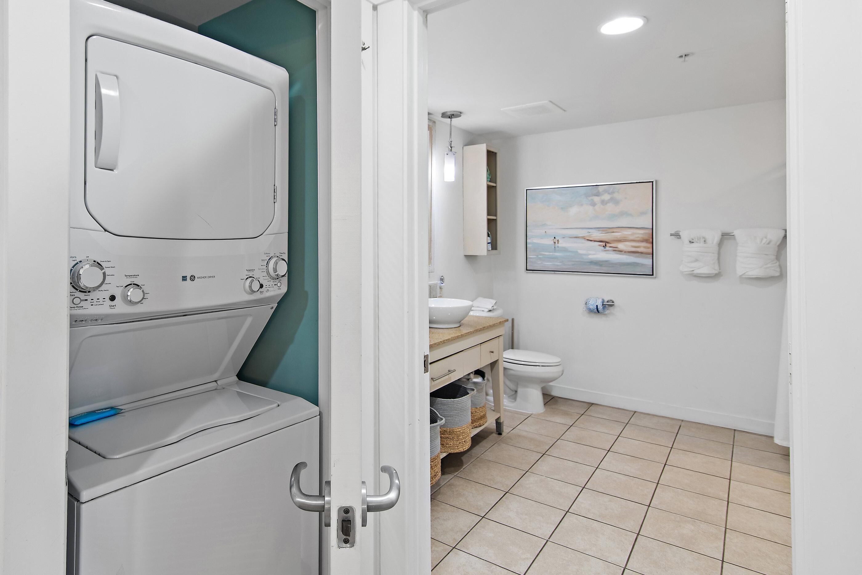 Ein Waschraum mit Waschmaschine und Trockner, ein Badezimmer mit Toilette, Waschbecken und einem Bild an der Wand.
