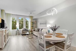 Una sala moderna con comedor, televisor y ventilador de techo.