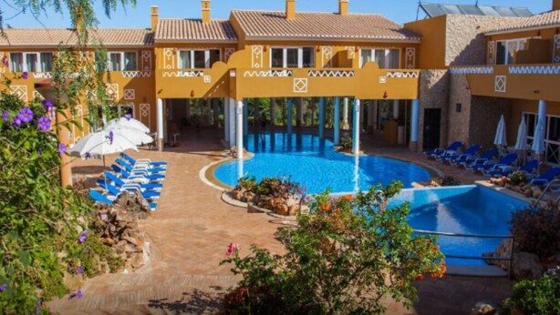A hotel with a swimming pool, sun loungers, and a covered area with umbrellas. - 1-Bedroom Apartment with Pool and Garden View (3 Adults) (Luz)