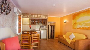 A compact living space with a kitchenette, a dining area, and a sofa. - 1-Bedroom Apartment with Pool and Garden View (3 Adults) (Luz)