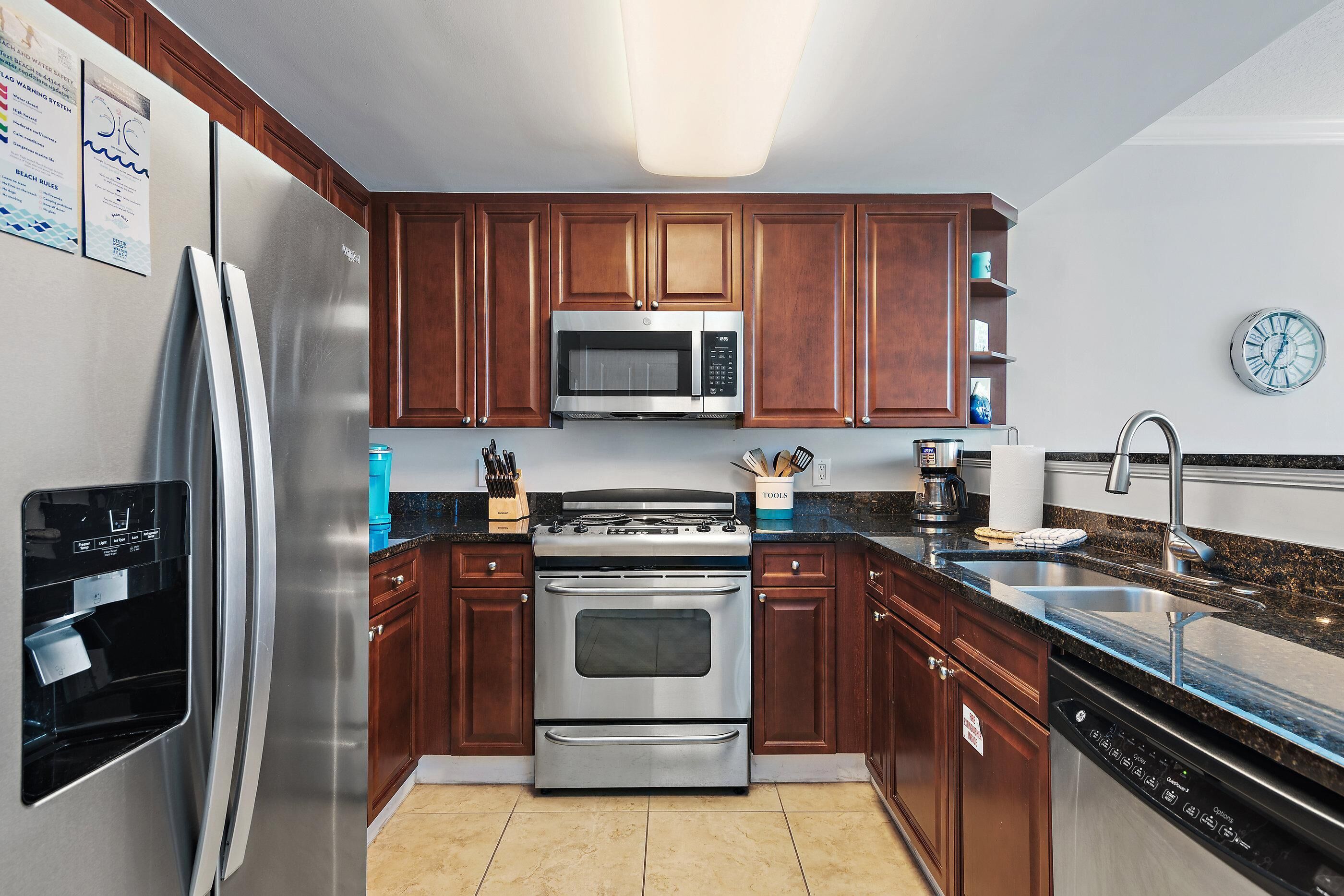 Una cocina con electrodomésticos de acero inoxidable, armarios de madera, un microondas y un fregadero.
