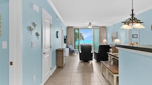 Un couloir d’hôtel donnant sur la mer, avec un ventilateur de plafond et un coin repas agrémenté d’un lustre.