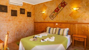 Une chambre d’hôtel avec un lit, une tête de lit en bois, deux tables de chevet, une couvre-lit verte et des appliques murales.