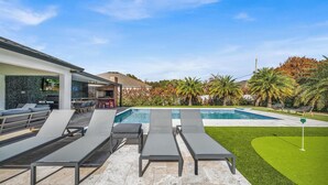 Un espace aménagé au bord de la piscine, avec des chaises longues, une piscine et une pelouse bien entretenue.