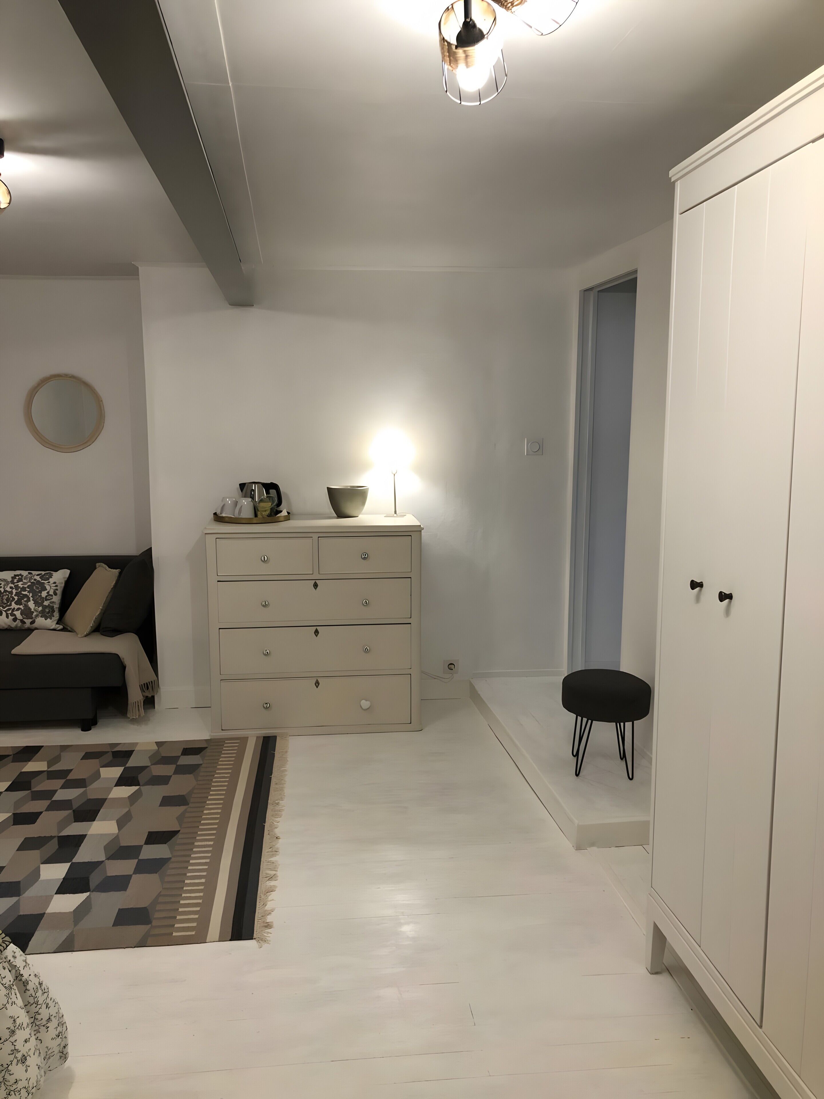 Une chambre à coucher comprenant un lit, une commode, une table de chevet, une armoire et un miroir.