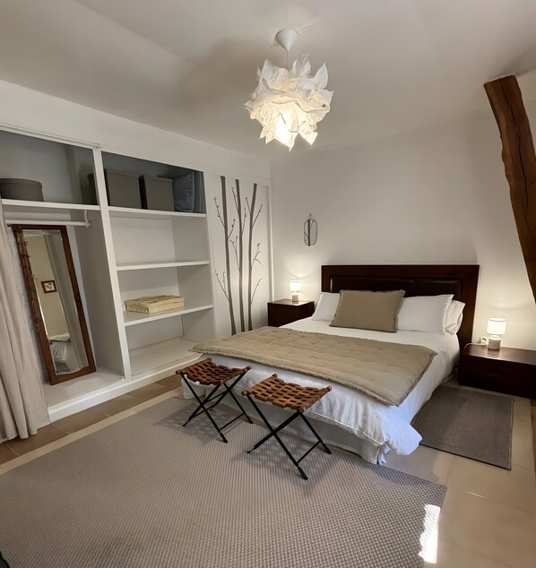 Un dormitorio con cama, dos mesitas de noche, un espejo, armario y una lámpara de techo original.