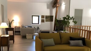 A living room with a sofa, a coffee table, a lamp, and a plant. - Guest Rooms “La Grande & La Jumelle” with Shared Terrace, Garden, and Wi-Fi (Soubrebost)