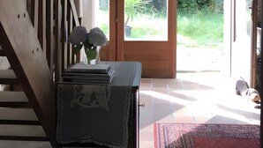 A room with a staircase, a large glass door leading to a garden, and a small table with a vase. - Guest Rooms “La Grande & La Jumelle” with Shared Terrace, Garden, and Wi-Fi (Soubrebost)